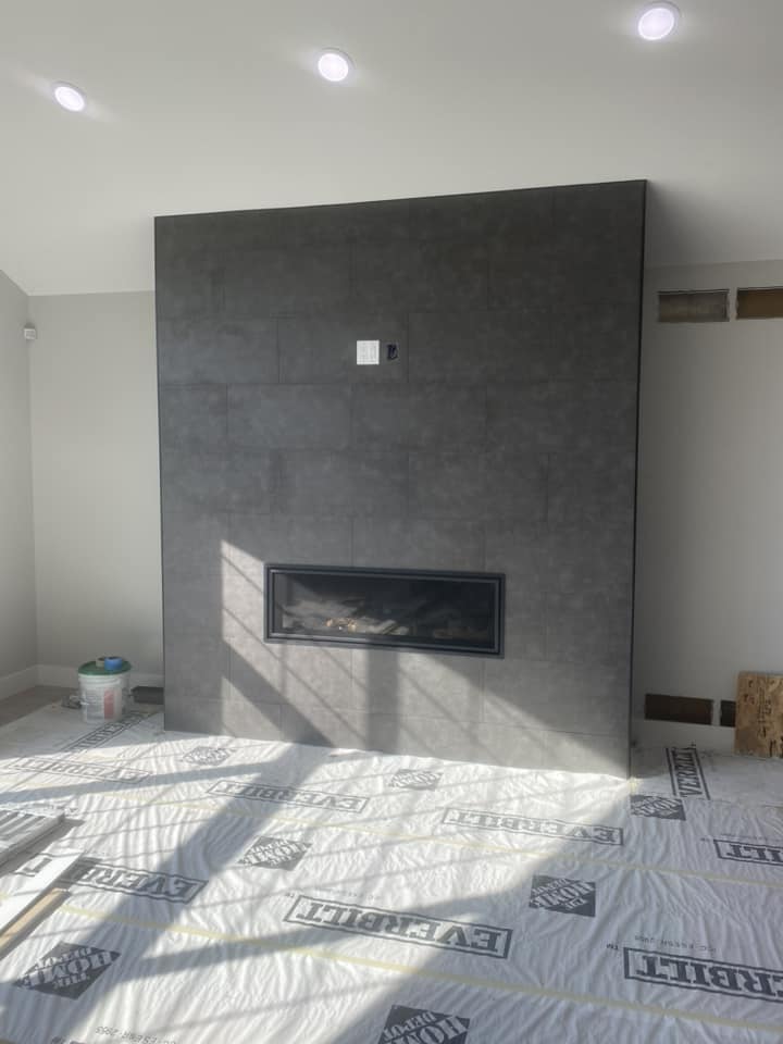Finished dark tile fireplace accent wall with linear gas fireplace insert, photographed straight-on at final stage